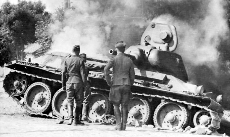 Немецкие солдаты осматривают подбитый танк Т-34. Лето 1941 года.  Эта машина оснащена литой башней, что было редкостью -большая часть «тридцатьчетверок» довоенного выпуска, тем более ранних, с пушкой Л-11, имела сварные башни.