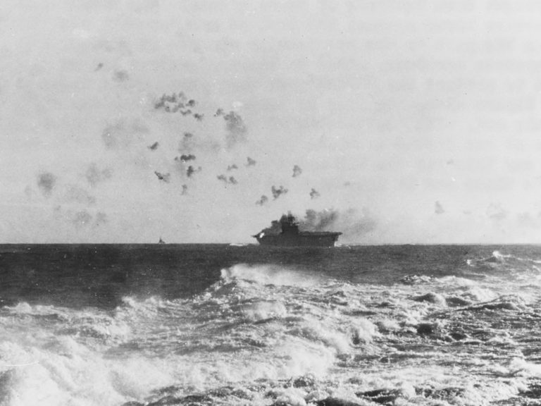 «Энтерпрайз» под японскими бомбами 24 августа 1942 года. Хорошо виден пожар в корме по правому борту и разрывы 127-мм зенитных снарядов history.navy.mil