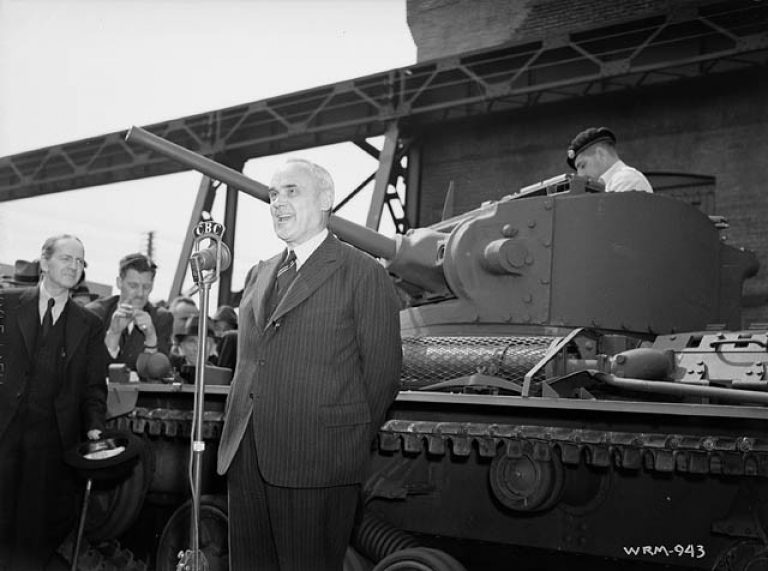 Министр вооружения и снабжения Кларенс Декейтер Хау читает речь на фоне первого Infantry Tank Mk.III, собранного в Канаде. Из башни танка выглядывает Стиртон – танкист, переживший эвакуацию из Дюнкерка. Монреаль, Квебек, 27 мая 1941 года.