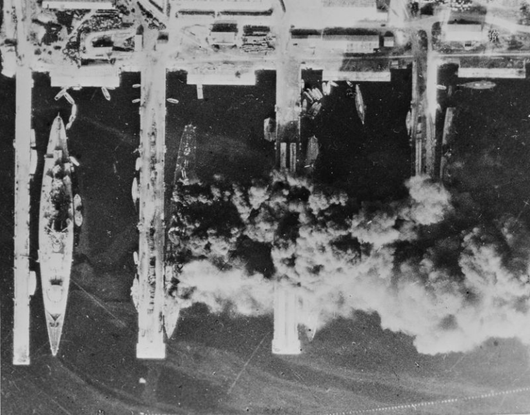 Французские корабли после затопления в Тулоне. Третий корабль слева — горящий тяжёлый крейсер Algérie, окутанный дымом