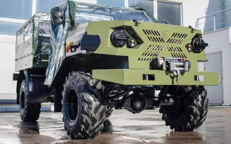Впереди установлен задний мост от Газели без поворотных кулаков. Колеса – вездеходные. Фары – с затемнением. На алюминиевой облицовке закреплена лопата.
